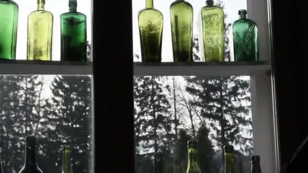 Diferentes tipos de botellas de colores en la ventana — Vídeo de stock