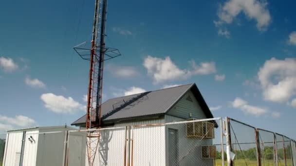 Höga cellulära tornet bredvid ett litet hus — Stockvideo