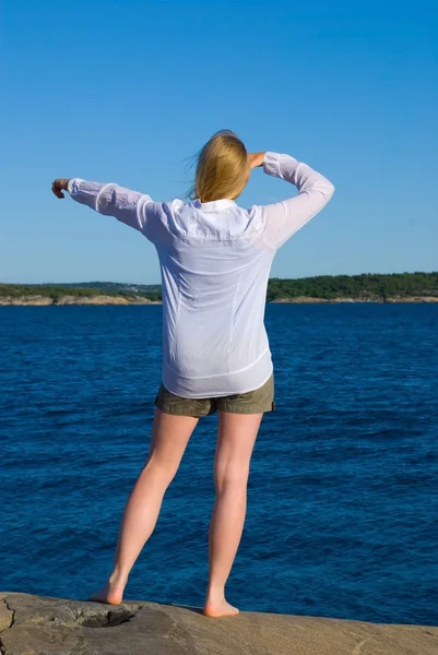 Woman standing at the coast and showing something — Stock Photo, Image