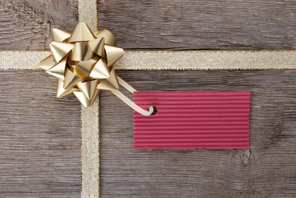 Golden bow and red tag as background — Stock Photo, Image