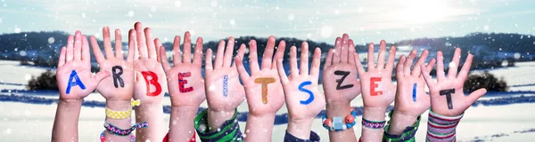 Mãos das crianças que constroem a palavra Arbeitszeit significa horas de trabalho, fundo do inverno — Fotografia de Stock