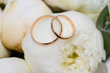 İki alyans ve beyaz laleler yakın.