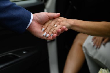 Adam kızın arabadan çıkmasına yardım ediyor. Eller yakın plan.