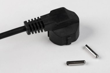 Siyah elektrik kablosu. Beyaz arka planda iki raptiye kırılmış. Çatal en altta.