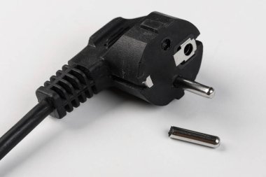 Beyaz arka planda kopmuş bir elektrik kablosu, bir pin kopmuş.