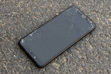 Asfaltta kırık dokunmatik ekranlı hasarlı akıllı telefon. seçici odak