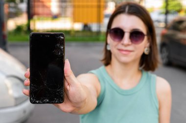 Kırık cam ekranlı akıllı telefon, üzgün bir kızın elinde.,
