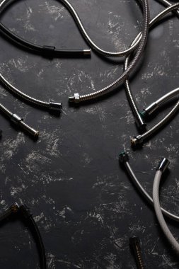 Koyu beton arka planda çok farklı duş hortumları var. Sanat fotoğrafçılığı