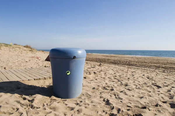 blue recycling bin on the beach