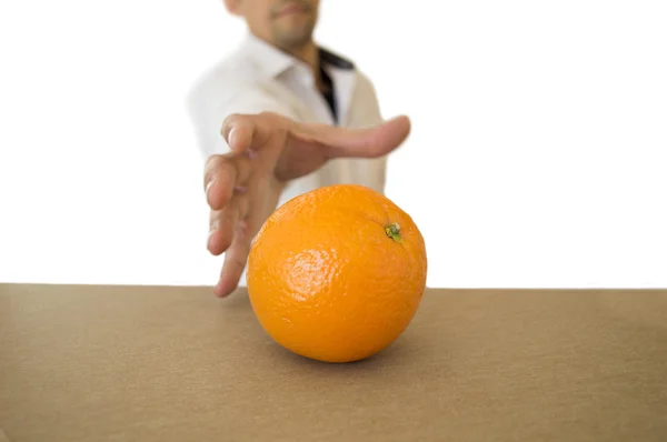 Άνθρωπος που πιάνει ένα πορτοκάλι στο τραπέζι — Φωτογραφία Αρχείου