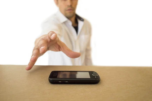 Homem pegando um telefone celular preto em uma mesa — Fotografia de Stock