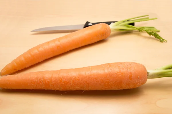 Duas cenouras e uma faca em uma mesa — Fotografia de Stock