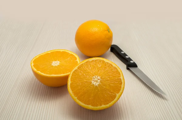 Whole orange and one departure and a knife on the table — Stock Photo, Image