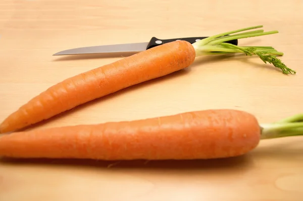 Dos zanahorias y un cuchillo en una mesa — Foto de Stock