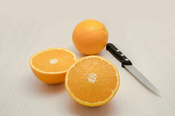 Whole orange and one departure and a knife on the table — Stock Photo, Image