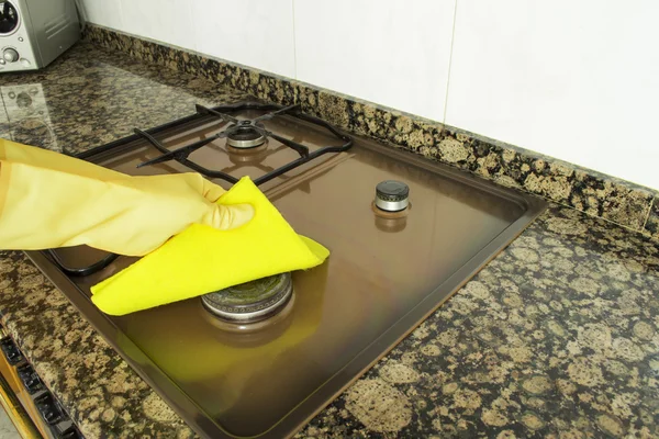 Donna pulizia bruciatore in cucina con panno giallo — Foto Stock