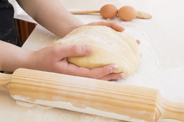 taking the dough with both hands together with a roller