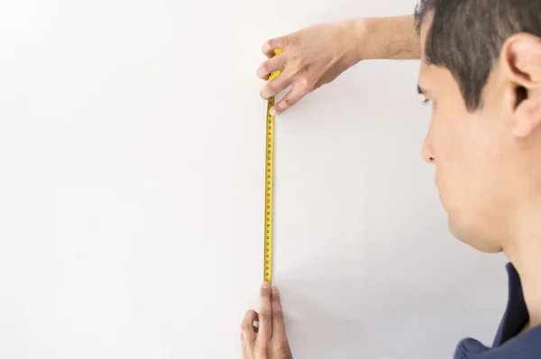 Closeup of man pointing at a measuring tape on the wall white — Stock Photo, Image