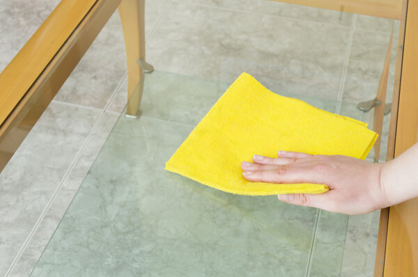 cleaning a glass table with yellow cloth