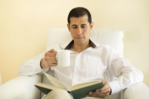 Hombre relajado leyendo un libro y bebiendo — Foto de Stock
