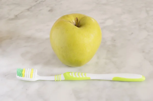 Τα μήλα με μια οδοντόβουρτσα που απομονώνονται σε μάρμαρο — Φωτογραφία Αρχείου