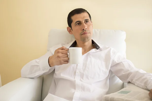 Man sitting drinking tea and thinking while reading a newspaper — Stock Photo, Image