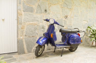 Kapının yanında bir taş evin önünde park edilmiş scooter