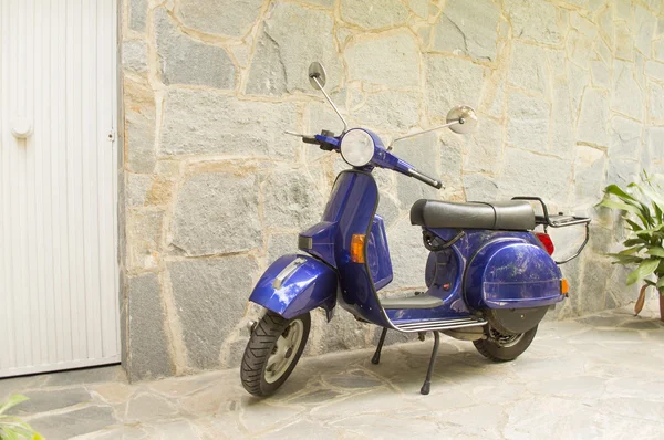 Scooter parked in front of a stone house near the door — Stock Photo, Image
