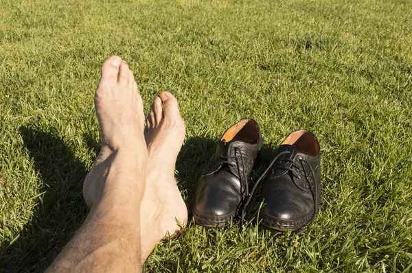 Pés relaxando na grama com seus sapatos — Fotografia de Stock