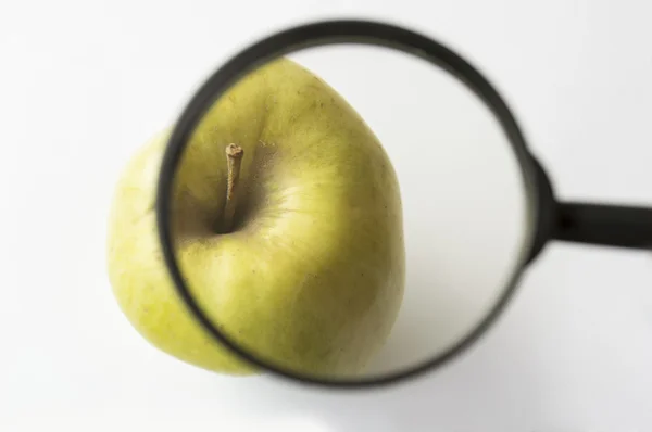 Reviewing an apple with a magnifying glass — Stock Photo, Image