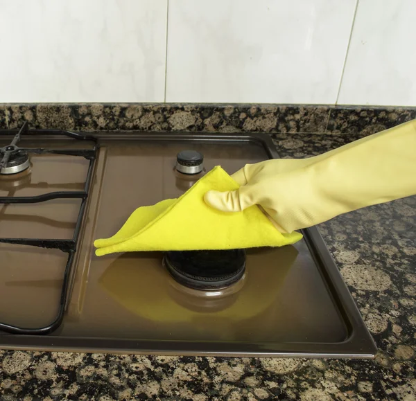 Cleaning Stove in the kitchen with yellow cloth — Stock Photo, Image