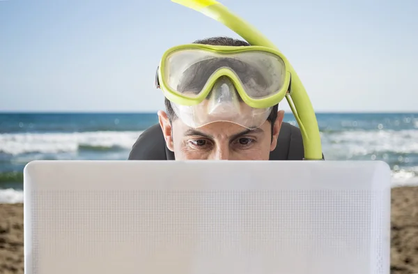 Homem sorrindo pelas ofertas na web para suas férias na praia — Fotografia de Stock