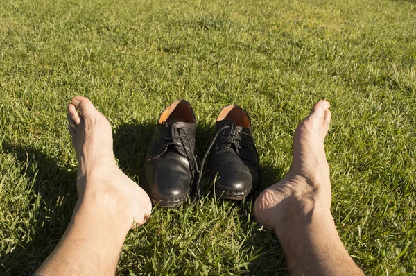 Ноги расслабляются в траве с его обуви — стоковое фото
