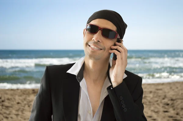 Amante latino chamando por telefone na praia — Fotografia de Stock