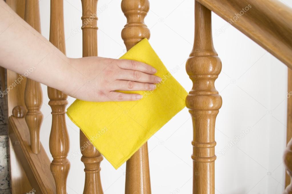 Cleaning wooden railing with yellow cloth horizontal