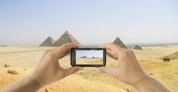 Tourist holds up camera mobile at pyramids — Stock Photo, Image