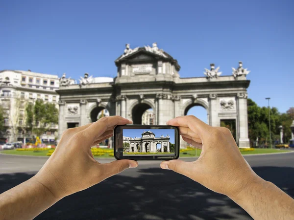 観光は、マドリードのプエルタ ・ デ ・ アルカラでカメラ付き携帯電話を保持します。 — ストック写真