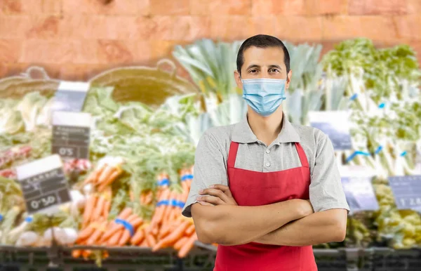 ラテンアメリカの労働者は コロナウイルスの拡散を避けるために顔文字を身に着けている間 果物や野菜を復元するスーパーマーケットで赤いエプロンを持つ パンデミックのライフスタイルの概念とコピースペース — ストック写真