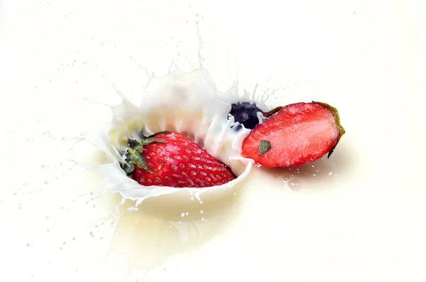 Delicious strawberry splashing into milk — Stock Photo, Image