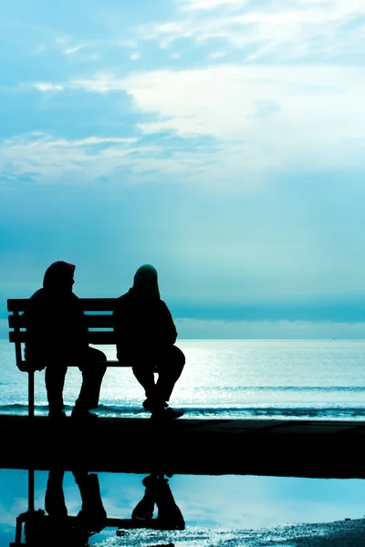 Δύο φίλοι, κάθεται στο παγκάκι ξύλο κοντά παραλία — Φωτογραφία Αρχείου