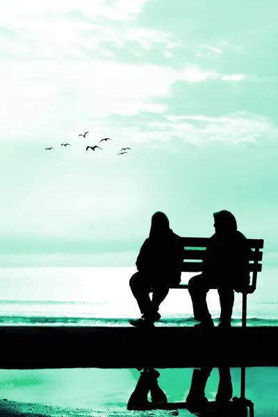 Two friends sitting on wood bench near beach — Stock Photo, Image