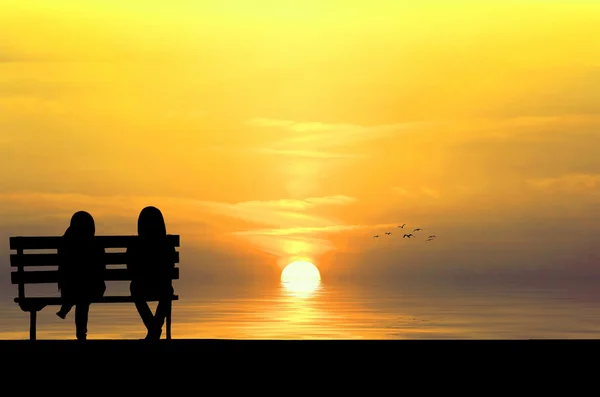 Two friends sitting on wood bench near beach — Stock Photo, Image