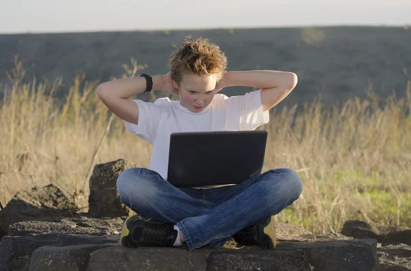 Descanso adolescente com laptop segurar as mãos atrás de sua cabeça — Fotografia de Stock