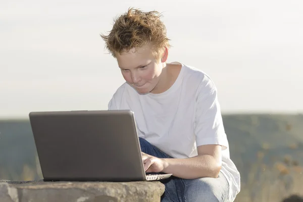 Skolpojke spela spelet på laptop — Stockfoto