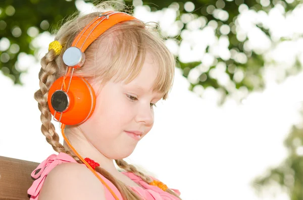 Girl sitting on bench in park and listening language audio cours — Stock Photo, Image