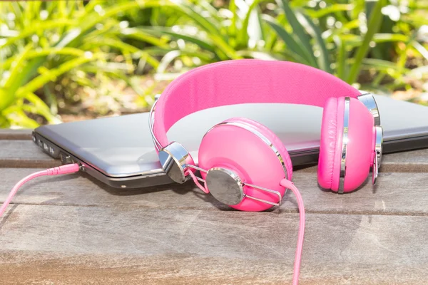 Auriculares rosados vivos coloridos y computadora portátil —  Fotos de Stock