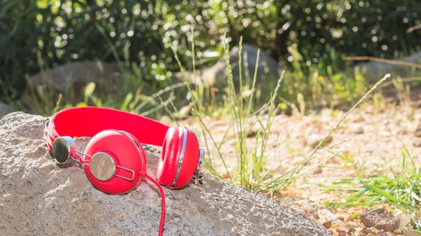 Bright red wired headphones on the rock — Stock Photo, Image