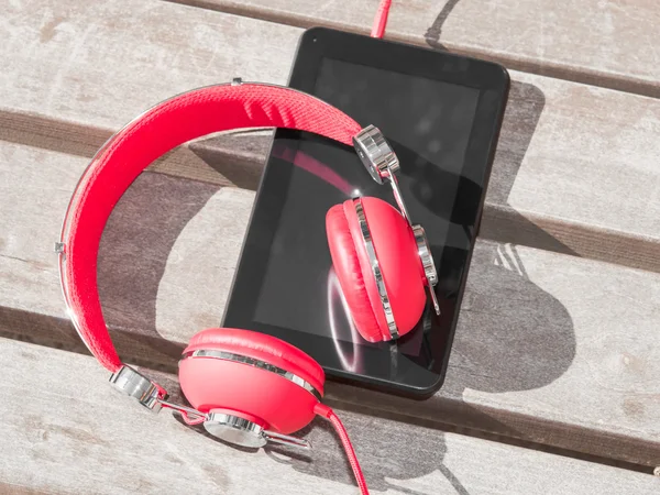 Fones de ouvido coloridos vermelhos e tablet PC — Fotografia de Stock