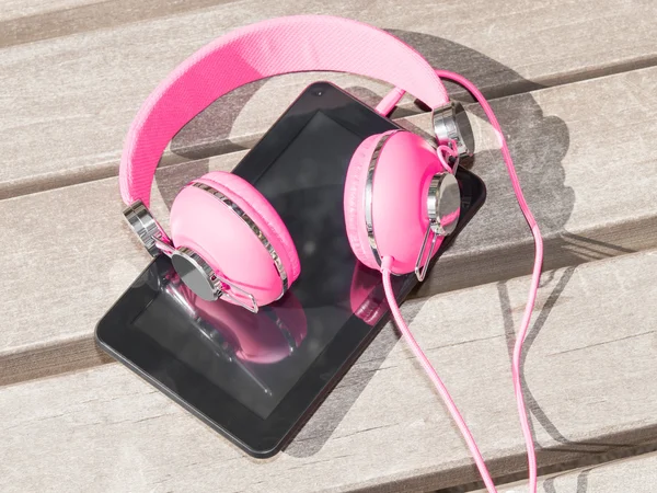 Fones de ouvido rosa feminino e tablet pc — Fotografia de Stock
