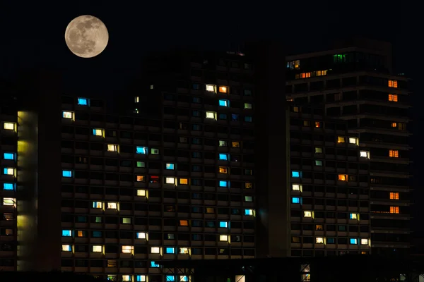 Vollmond über bunten Fenstern von Wohnhaus lizenzfreie Stockfotos